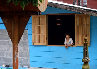 girl stands in new window with wooden shutters that lock