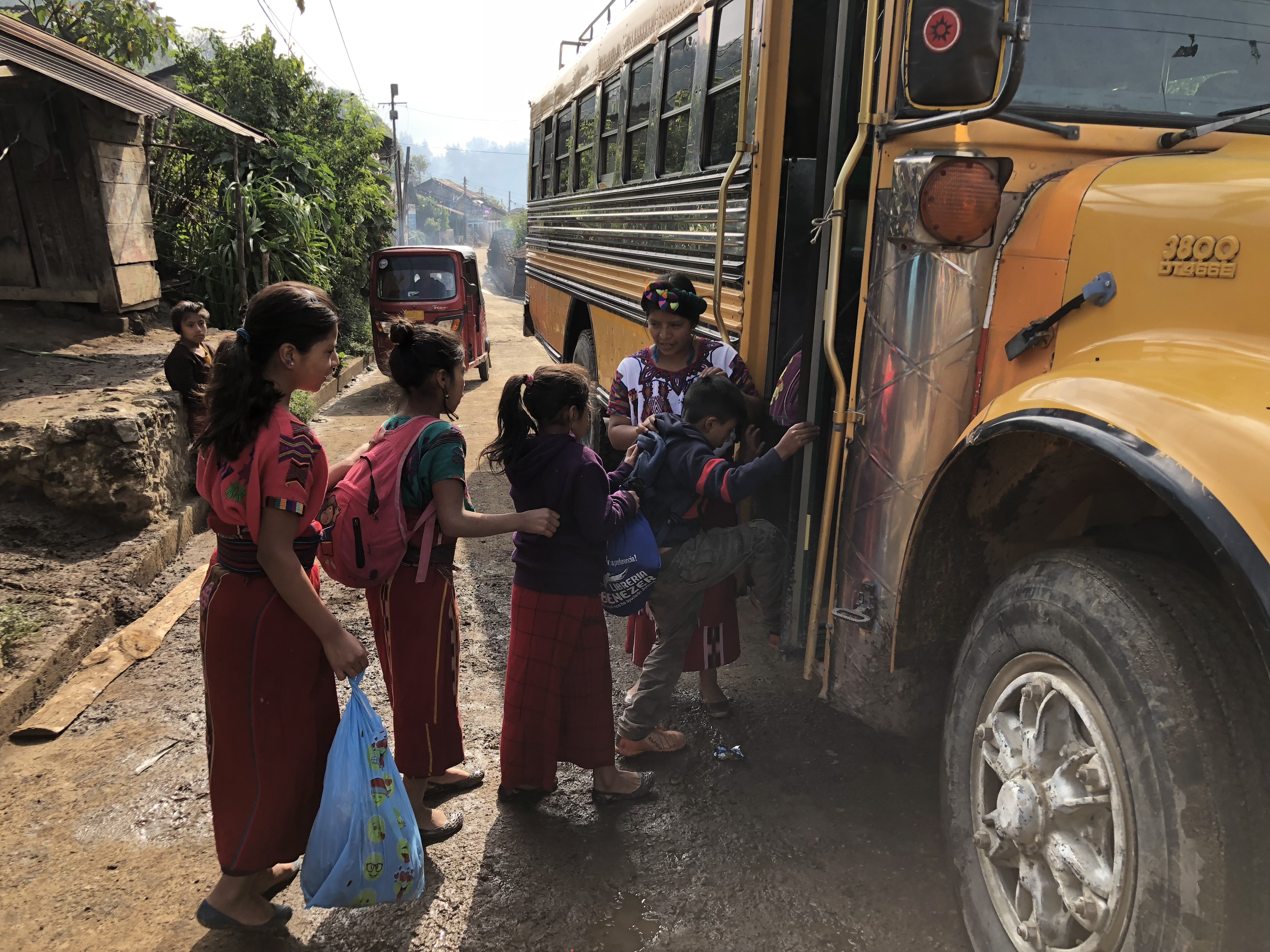 teacher watches as kids get into a schoolbus