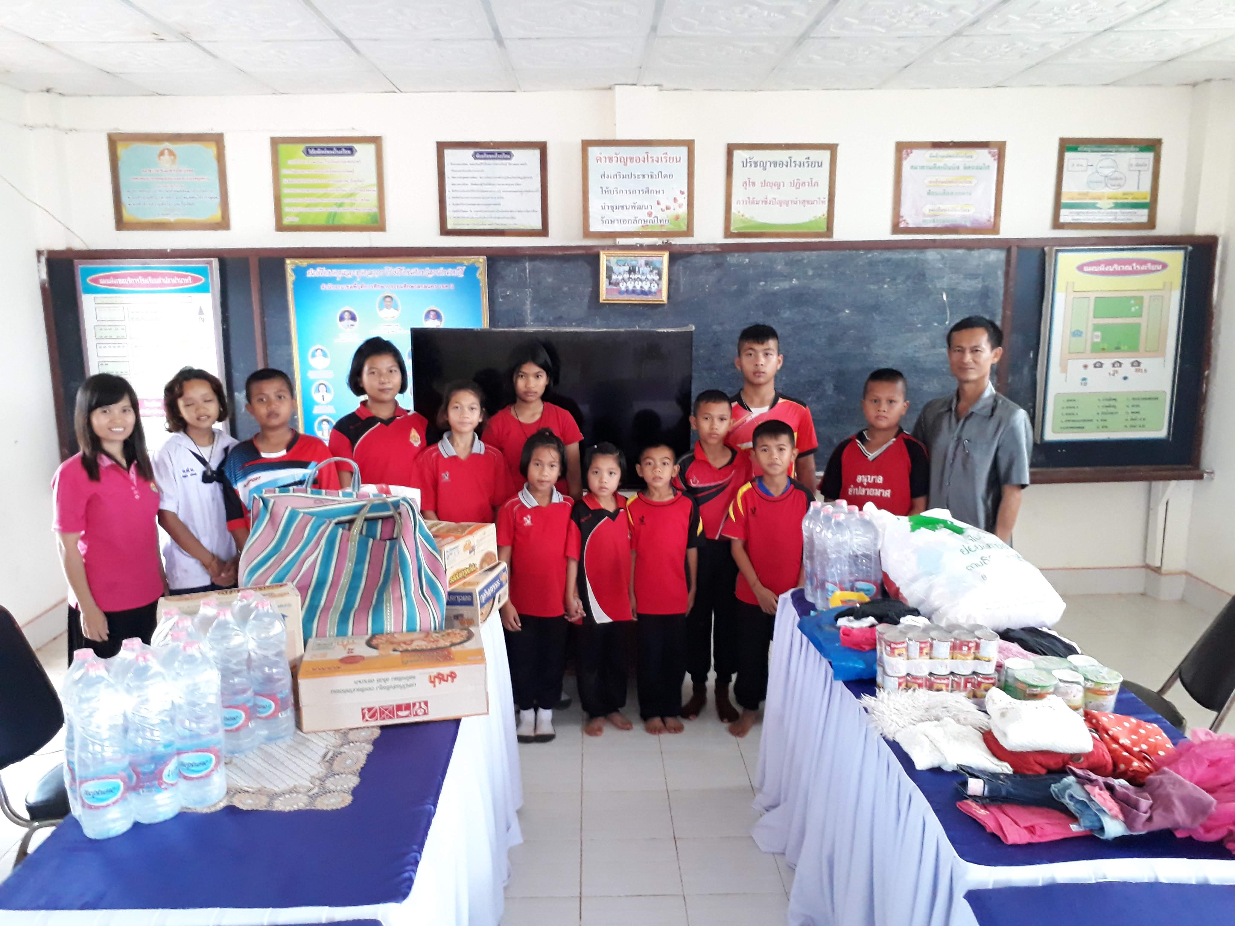 thai students and teacher pose with food, water and clothing