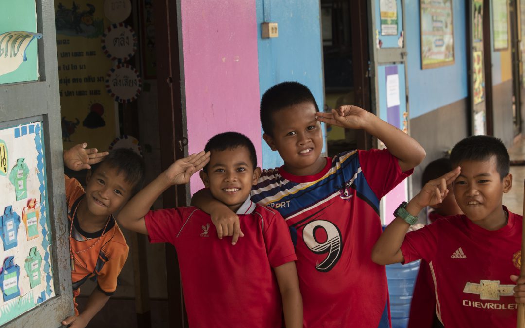 four young Thai boys at school salute the camera