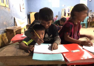 two students from CEMIK writing in their notebooks in a classroom
