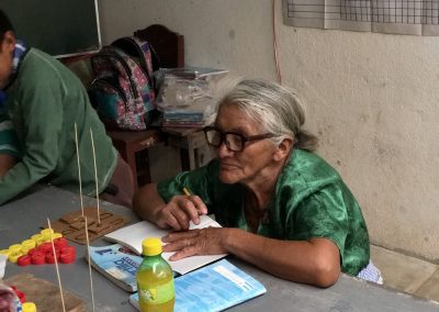 an old woman in the adult literacy program in Guatemala focuses on an open workbook in front of her