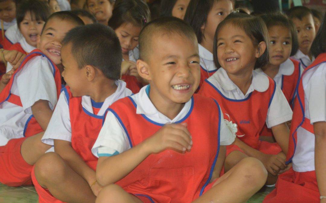 young thai boy smiles in his red school vest