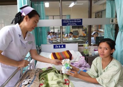 Thai nurse gives a new mom a bundle of baby clothes in the hospital