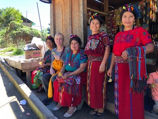 group of Guatemalan women from CEMIK sit with Joan and smile for the camera