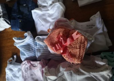 a stack of baby clothes tied together with a ribbon, sitting on top of a pile of more baby clothes