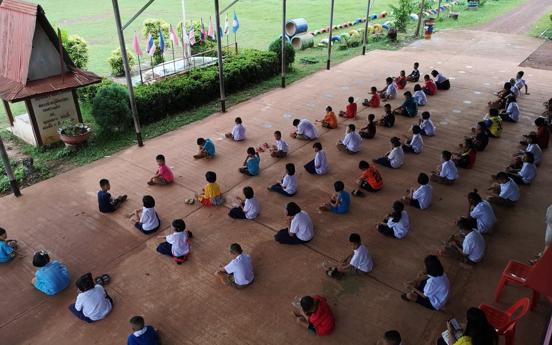 group of students sit while social distancing during meditation at school Thailand