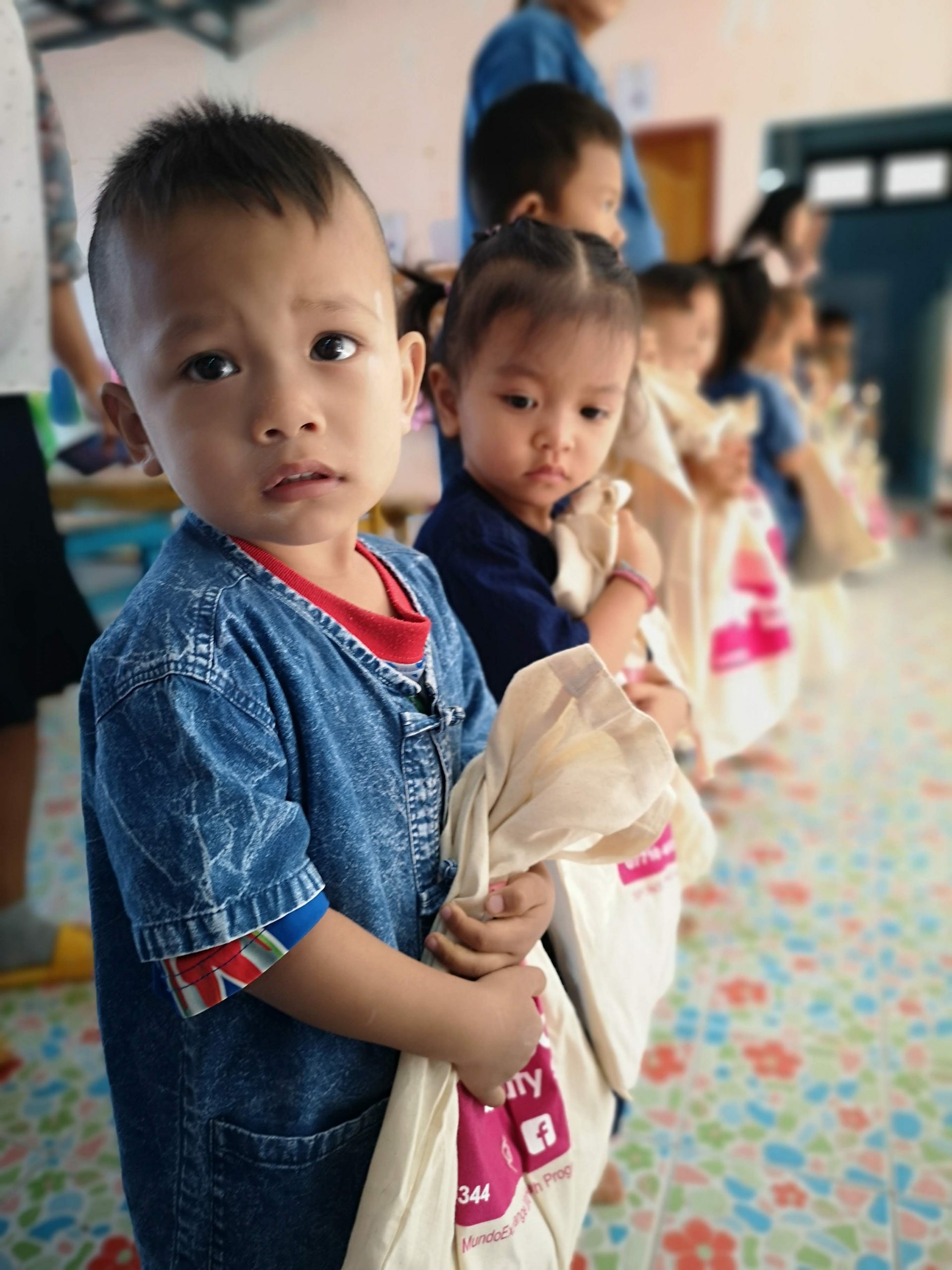 young boy looks into the camera while holding a donation bag with school supplies