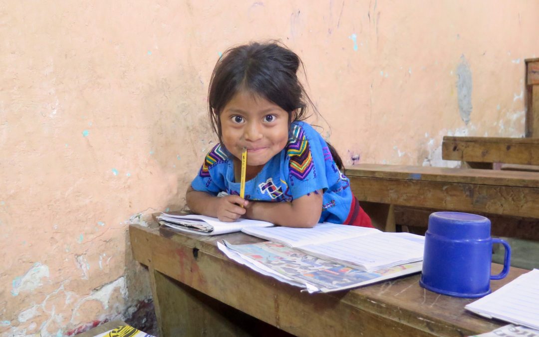 educational Center little girl smiles at the camera with her homework in front of her