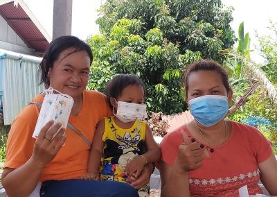 two Thai women and a kid pose while wearing surgical masks
