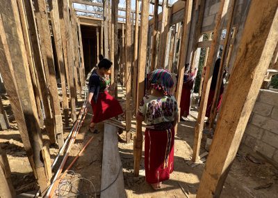 Guatemalan women stand in a construction site with wooden beams up for support