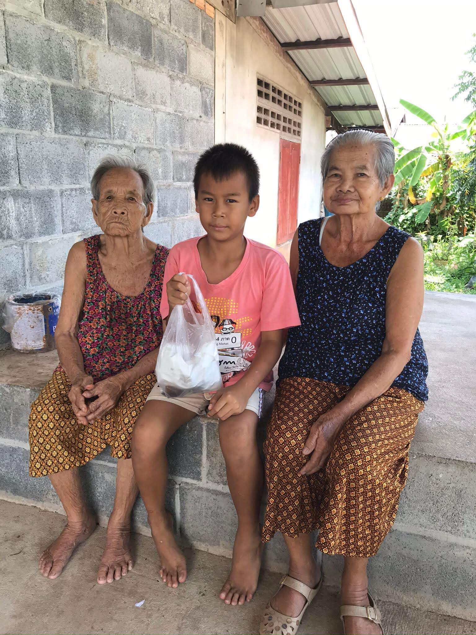 Thai elder Mun sits with her grandson and a fellow village woman