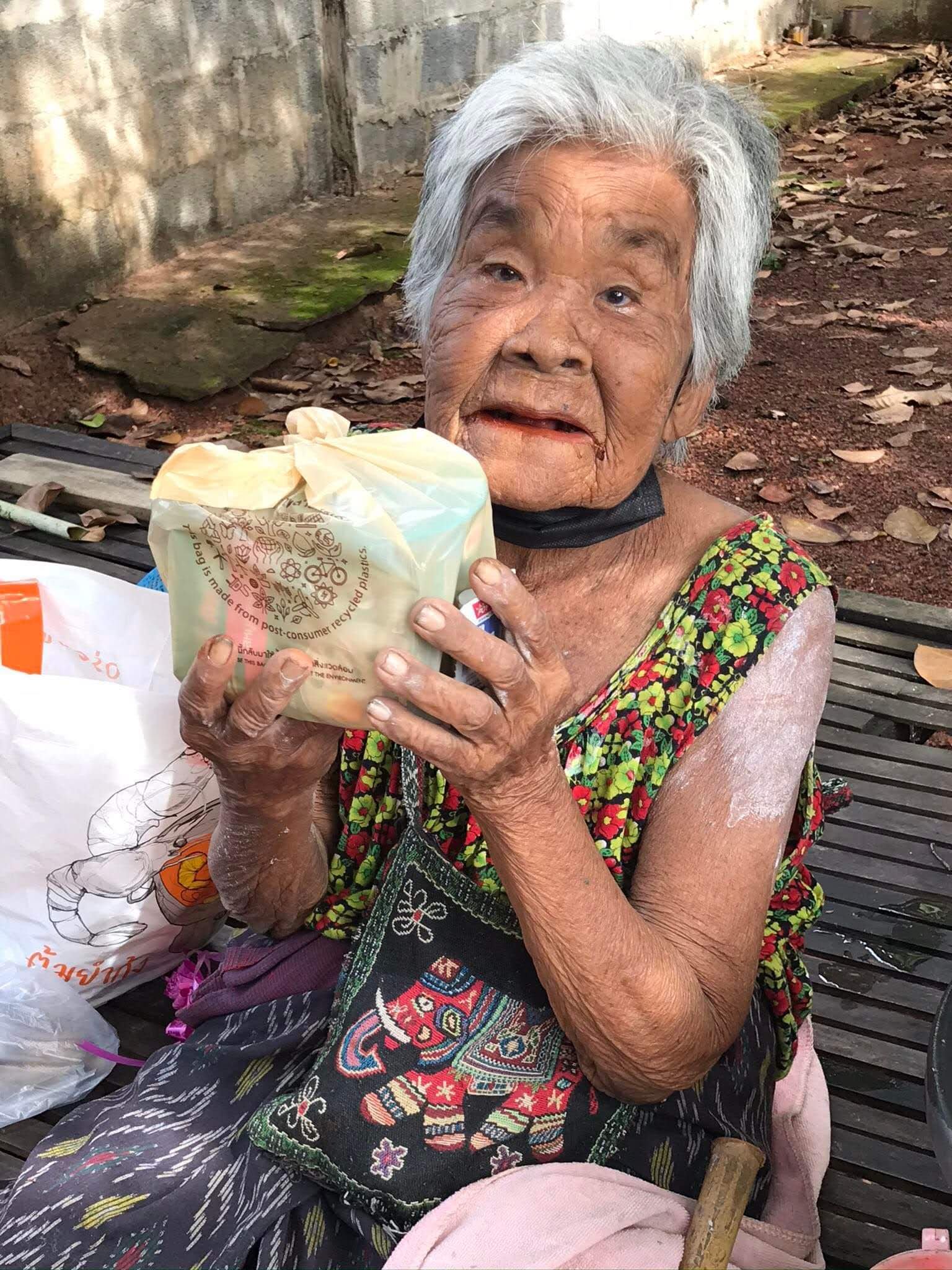 Thai eler woman Yaai Charlie holding up food for the camera