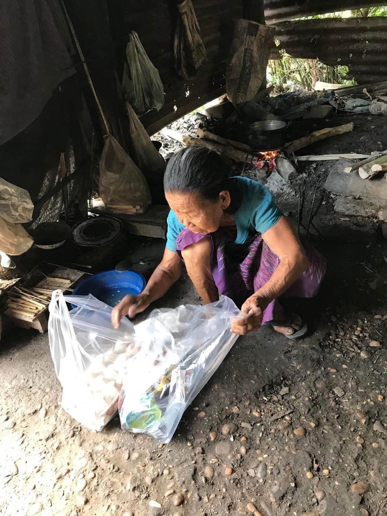 elder pa Ruay on the ground looking at a bag of food