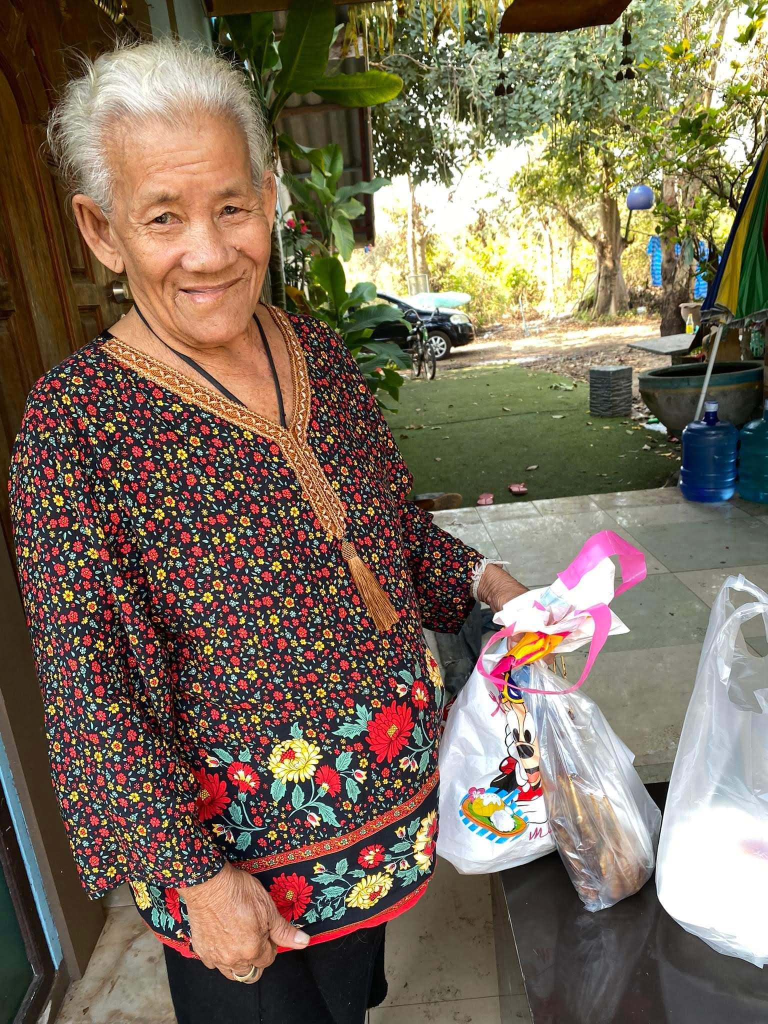 thai elder woman Nong standing with a bag of food