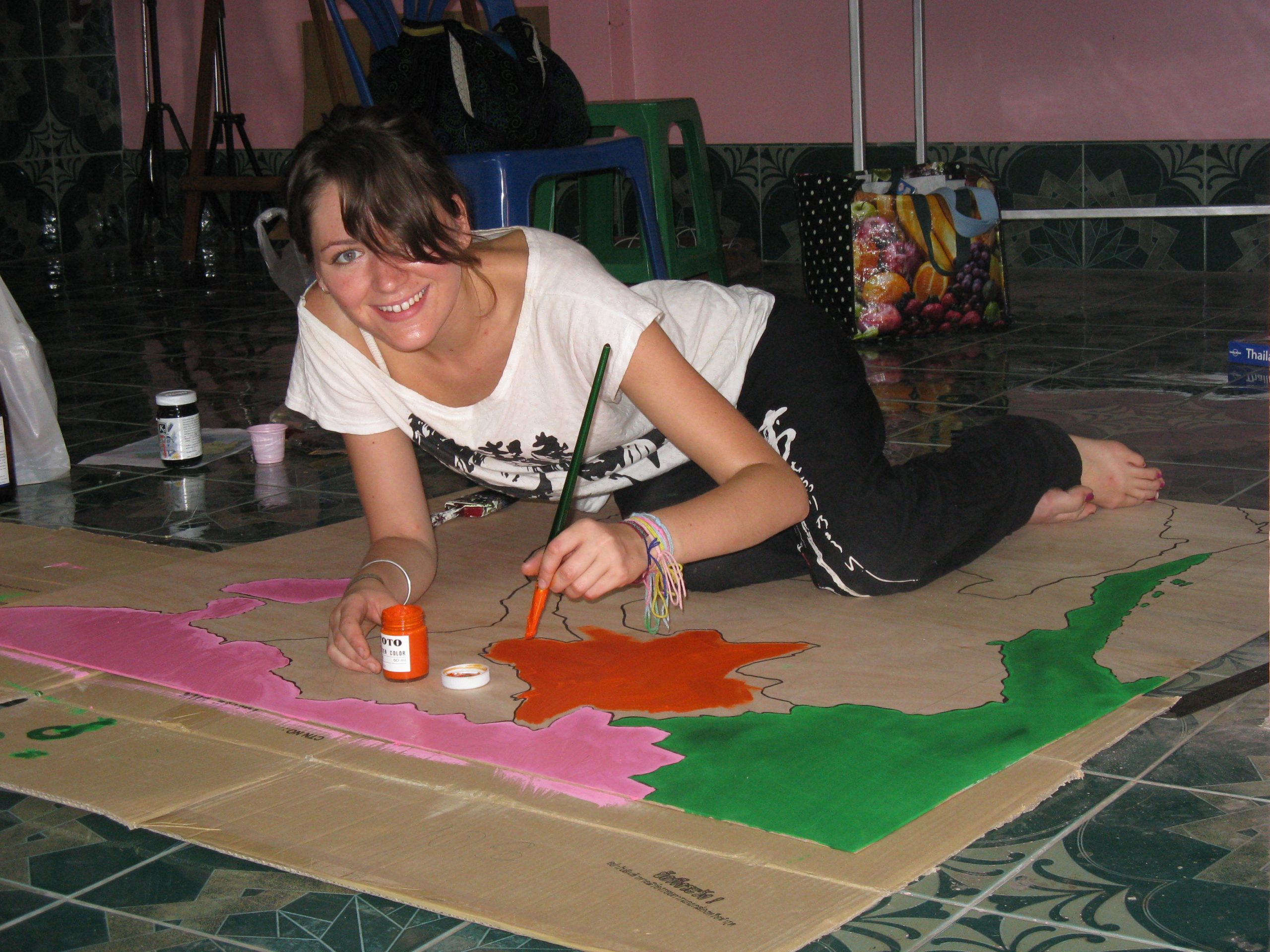 Kelly art project painting Isaan Thailand Kelly lays on the ground painting a poster