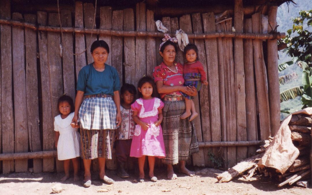Guatemalan family stands in front of their house