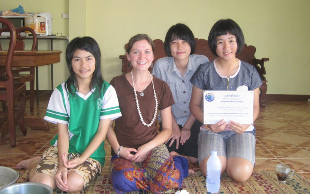 Volunteer Kelly sits with three young Thai students