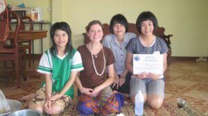 Volunteer Kelly sits with three young Thai students